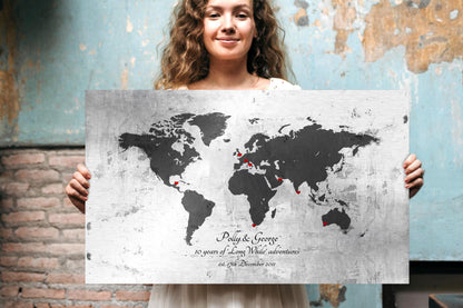Woman holding a vintage tin world map wall art with names, established date and heart location markers, 10th anniversary