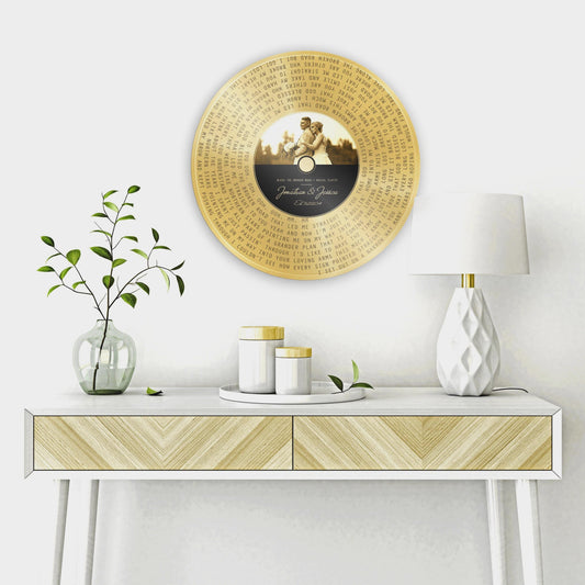 Custom Brass Anniversary Song Record Plaque hangs on a wall above a table. The record label is customized with a portrait and the song title, artist name and the couple's names and union date.

Courtesy of Honeycomb Proverbs