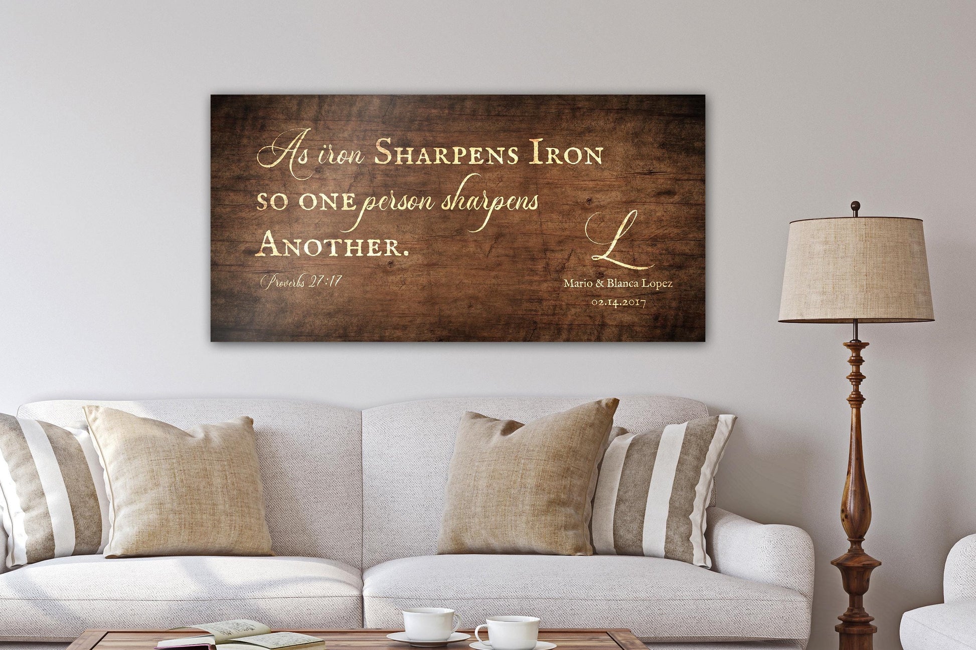 A handcrafted and personalized rustic wooden sign hangs above a linen sofa in "Stained Birch" finish - one of four finish options. The bible verse, "As iron sharpens iron; so one person sharpens another" as well as the names and established date of the recipients' are included on this handcrafted rustic wall decor.

Courtesy of Honeycomb Proverbs