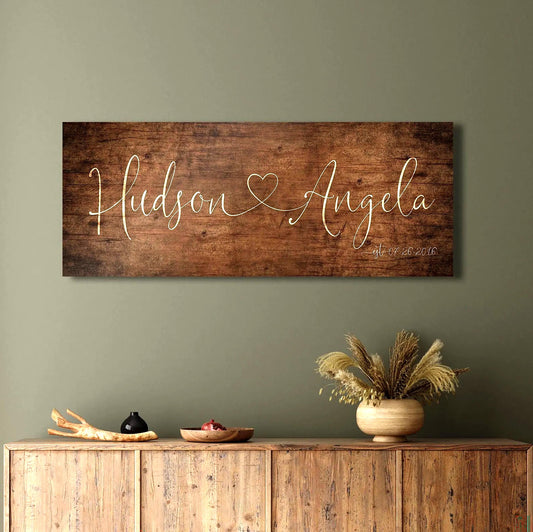 One Heart Between Us: Couples Rustic Name Sign
A rustic wood sign featuring the names of a couple in whimsical calligraphy, connected by a single heart, hangs above a sideboard in a distressed aged birch finish. 
Courtesy of Honeycomb Proverbs