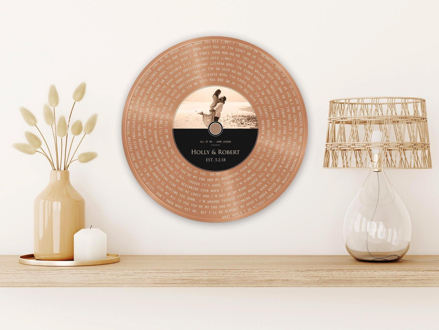 Metal vinyl record wall decor or plaque featured in copper with a personalized inscription for Holly & Robert, established in 2018. The record features a photo of a couple on the label. The song lyrics of their wedding song are inscribed into the copper "vinyl" portion of the record.