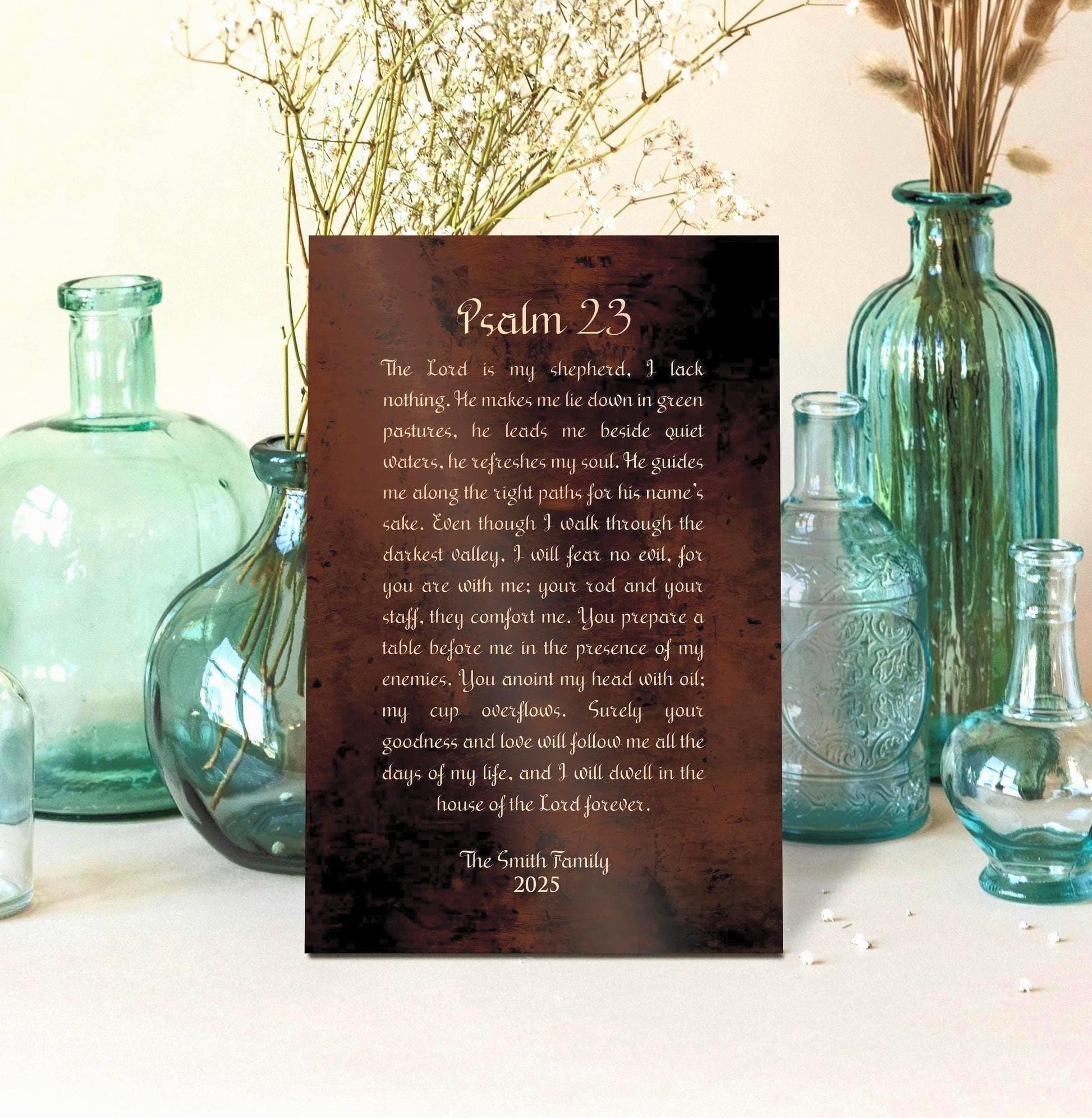 Personalized Psalm 23 Burnished Bronze Metal Plaque is center frame, surrounded by decorative glass-blown vessels and vases. The words of Psalm 23 are inscribed in old world script and "The Smith Family" and their established date is included beneath the Scripture inscription.  Photo courtesy of Honeycomb Proverbs
