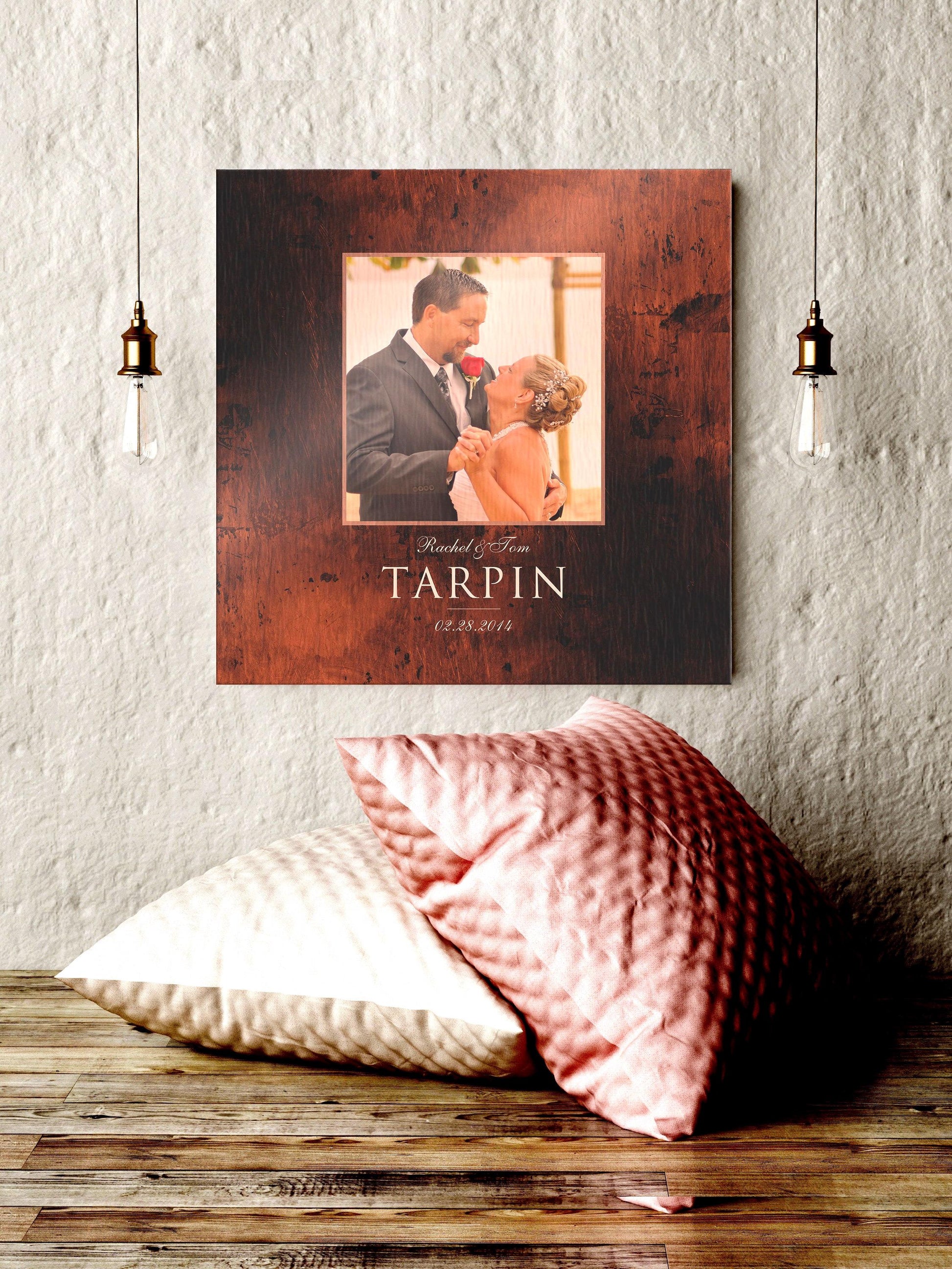 Square, burnished-bronze photo plaque with a square photo of a bride and groom embracing in the upper center portion names and date beneath. The first names are scripted in calligraphy on the top line and the last name sits in a bold large typeface below. the established date sits under the last name in calligraphy.