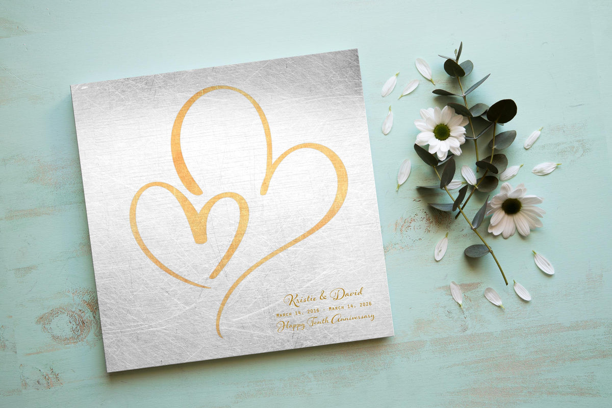Distressed tin anniversary plaque with brass-toned nested hearts and first names, a 10th anniversary tin gift