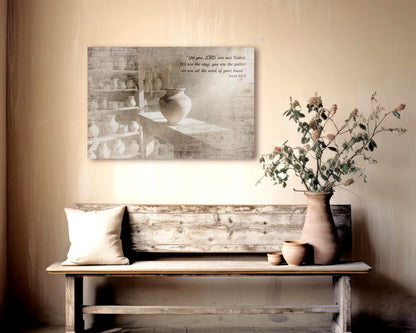 Wood Christian Wall Art, aged and weathered wood, image of a clay pot in a workshop and the bible verse Isaiah 64:8 "Yet you, LORD, are our Father. We are the clay, you are the potter; we are all the work of your hand" is inscribed in a casual calligraphy on the upper right corner.